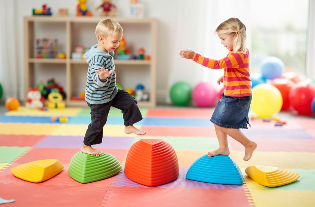Enfants s'amusant en équilibre sur des plots de motricité colorés dans une salle de gymnastique.